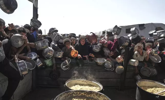 Palestinians struggle to obtain donated food at a community kitchen in Khan Younis, in the southern Gaza Strip, Friday, May 9, 2025. (AP Photo/Abdel Kareem Hana)
