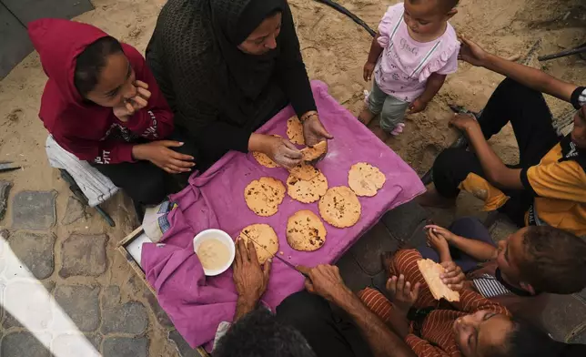 Nevin Qassim, a displaced Palestinian woman, and her family eat bread she baked from ground lentils as a substitute amid a flour shortage in the Gaza Strip, in Khan Younis, on Sunday, May 11, 2025. (AP Photo/Abdel Kareem Hana)