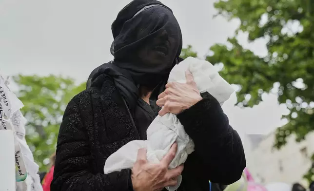 A protester holds a mock baby during a demonstration to commemorate the Nakba Day in Berlin, Germany, Thursday, May 15, 2025. (AP Photo/Ebrahim Noroozi)