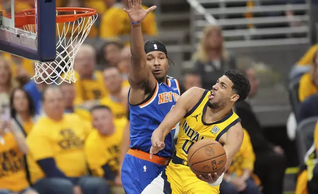 Indiana Pacers guard Tyrese Haliburton (0) shoots the ball past New York Knicks guard Miles McBride, left, during the second half of Game 4 of the Eastern Conference finals of the NBA basketball playoffs in Indianapolis, Tuesday, May 27, 2025. (AP Photo/Michael Conroy)