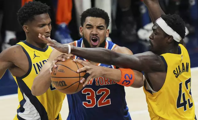 New York Knicks center Karl-Anthony Towns (32) tries to get past Indiana Pacers forward Pascal Siakam (43) and Indiana Pacers guard Bennedict Mathurin, left, during the first half of Game 4 of the Eastern Conference finals of the NBA basketball playoffs in Indianapolis, Tuesday, May 27, 2025. (AP Photo/AJ Mast)