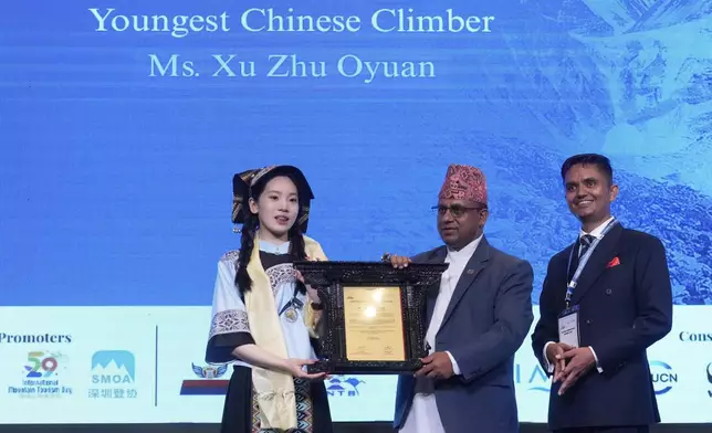 Xu Zhu Oyuan, the youngest Chinese climber to summit Mount Everest, receives an honorary certificate from Badri Prasad Pandey, Nepal's Minister for Culture, Tourism, and Civil Aviation, during the Everest Summiteers Summit in Kathmandu, Nepal, on Tuesday, May 27, 2025. (AP Photo/Niranjan Shrestha)