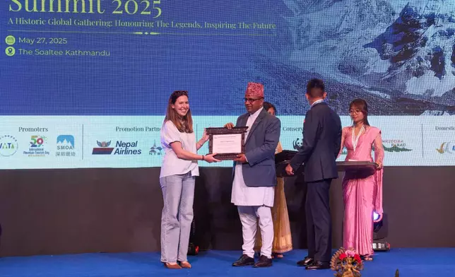 Adriana Brownlee, the youngest female to summit Mount Everest, receives an honorary certificate from Badri Prasad Pandey, Nepal's Minister for Culture, Tourism, and Civil Aviation, during the Everest Summiteers Summit in Kathmandu, Nepal, on Tuesday, May 27, 2025. (AP Photo/Niranjan Shrestha)