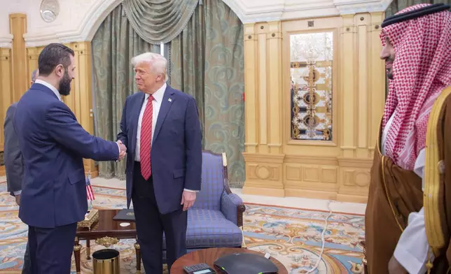In this photo released by the Saudi Royal Palace, Syria's interim President Ahmad al-Sharaa, left, shakes hands with President Donald Trump, centre, in Riyadh, Saudi Arabia, Wednesday, May 14, 2025. At right is Saudi Crown Prince Mohammed bin Salman.(Bandar Aljaloud/Saudi Royal Palace via AP)