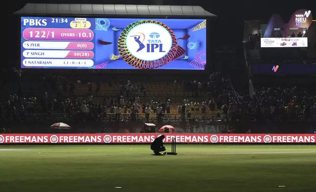 A worker removes the equipment placed next to the stumps after the authorities asked to evacuate the stadium during the Indian Premier League cricket match between Punjab Kings and Delhi Capitals at Himachal Pradesh Cricket Association Stadium in Dharamshala, India, Thursday, May 8, 2025. (AP Photo/Ashwini Bhatia)