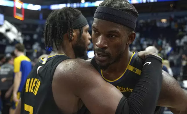 Golden State Warriors guard Buddy Hield (7), left, and forward Jimmy Butler (10) hug after Game 1 of an NBA basketball second-round playoff series against the Minnesota Timberwolves, Tuesday, May 6, 2025, in Minneapolis. (AP Photo/Abbie Parr)