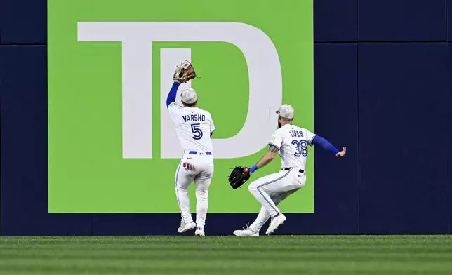 Toronto Blue Jays center fielder Daulton Varsho (5) plays a double hit by Detroit Tigers' Spencer Torkelson off the wall in first-inning baseball game action in Toronto, Sunday, May 18, 2025. (Jon Blacker/The Canadian Press via AP)