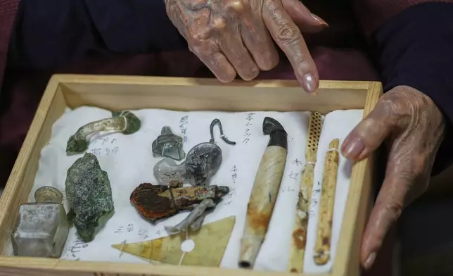 Fumi Takeshita, a survivor of the 1945 Nagasaki atomic bombing, shows preserved artifacts damaged by the atomic bomb in Nagasaki, southern Japan, Friday, April 25, 2025. (AP Photo/Eugene Hoshiko)