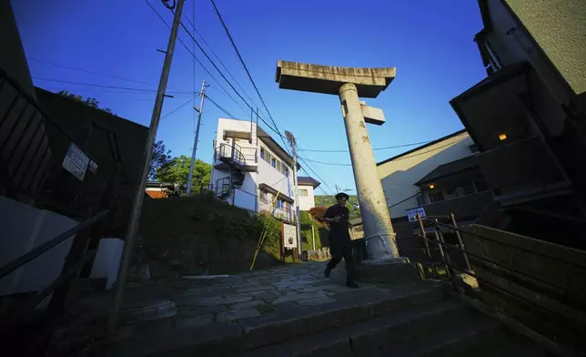 A person walks past the One-Pillar Torii Gate at Sannō Shrine, the only gate remaining of four gates after the 1945 atomic bombing in Nagasaki, southern Japan, Friday, April 25, 2025. (AP Photo/Eugene Hoshiko)