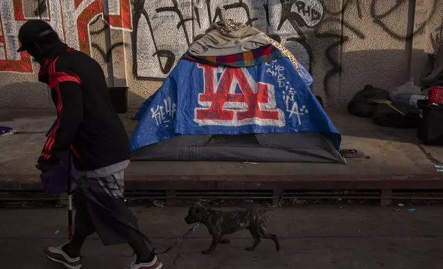 FILE - A man walks past a homeless encampment in downtown Los Angeles, Oct. 25, 2023. (AP Photo/Jae C. Hong, File)