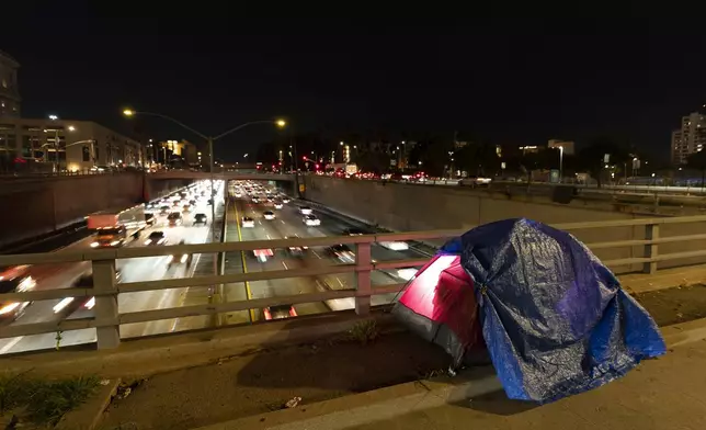 FILE - A tarp covers a portion of a homeless person's tent on a bridge overlooking the 101 Freeway in Los Angeles, Feb. 2, 2023. (AP Photo/Jae C. Hong, File)