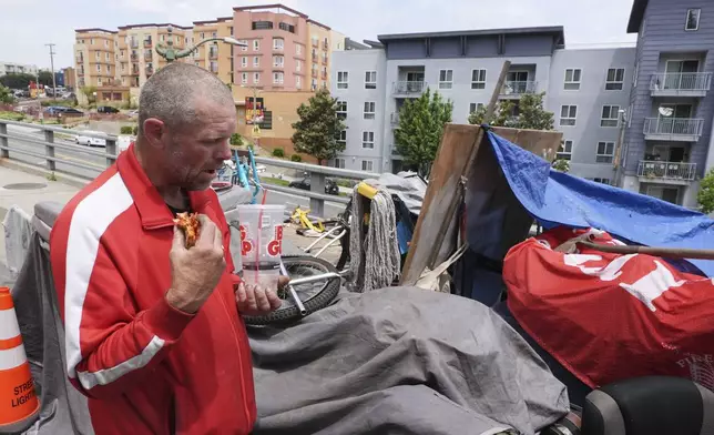 Scott Robertson Serge eats lunch in a homeless encampment where he currently lives, Monday, May 12, 2025, in Los Angeles. (AP Photo/Damian Dovarganes)