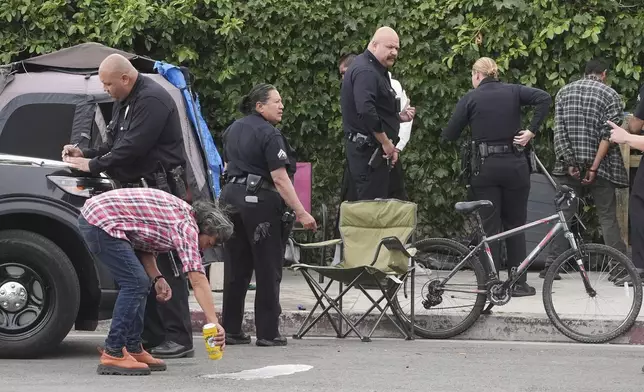 Two people are cited for drinking in public at a homeless encampment, Monday, May 12, 2025, in Los Angeles. (AP Photo/Damian Dovarganes)