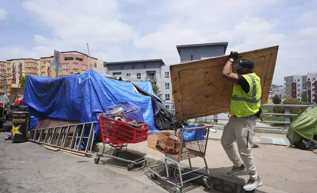Jay Joshua cleans up around a homeless encampment where he currently lives, Monday, May 12, 2025, in Los Angeles. (AP Photo/Damian Dovarganes)