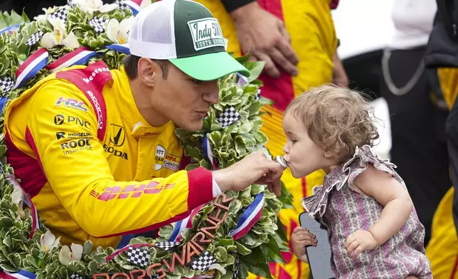 Alex Palou, left, of Spain, has his winner's ring kissed by his daughter Lucia on the Yard of Bricks on the start/finish line after winning the Indianapolis 500 auto race at Indianapolis Motor Speedway in Indianapolis, Sunday, May 25, 2025. (AP Photo/AJ Mast)