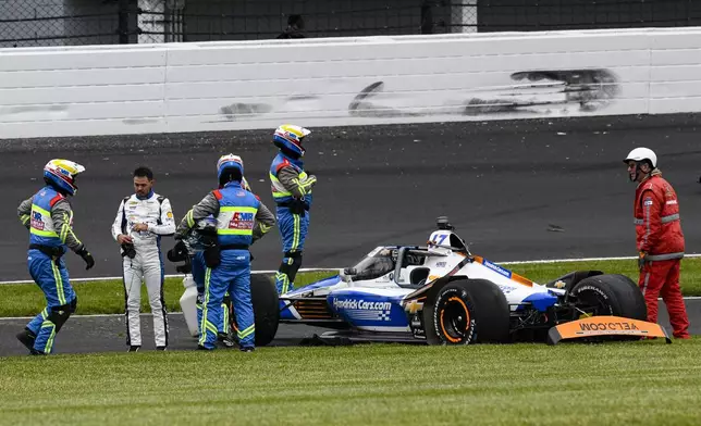 Kyle Larson, second from left, is checked after he hit the wall in the second turn during Indianapolis 500 auto race at Indianapolis Motor Speedway in Indianapolis, Sunday, May 25, 2025. (AP Photo/Jamie Gallagher)
