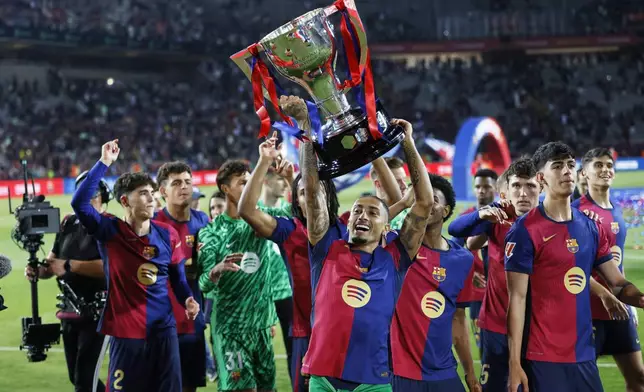 Barcelona's Raphinha lifts the trophy during celebration of winning the La Liga after the Spanish La Liga soccer match between Barcelona and Villarreal at Lluis Companys Olympic Stadium in Barcelona, Spain, Sunday, May 18, 2025. (AP Photo/Joan Monfort)