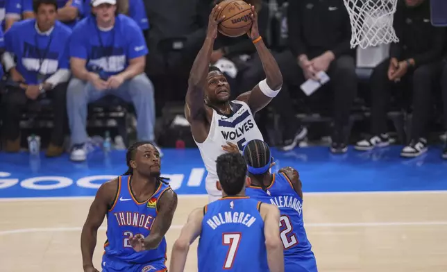 Minnesota Timberwolves guard Anthony Edwards, top, goes up for a basket agains Oklahoma City Thunder guard Cason Wallace (22), forward Chet Holmgren (7) and guard Shai Gilgeous-Alexander (2) during the first half of Game 2 of an NBA basketball Western Conference Finals playoff series Thursday, May 22, 2025, in Oklahoma City. (AP Photo/Nate Billings)