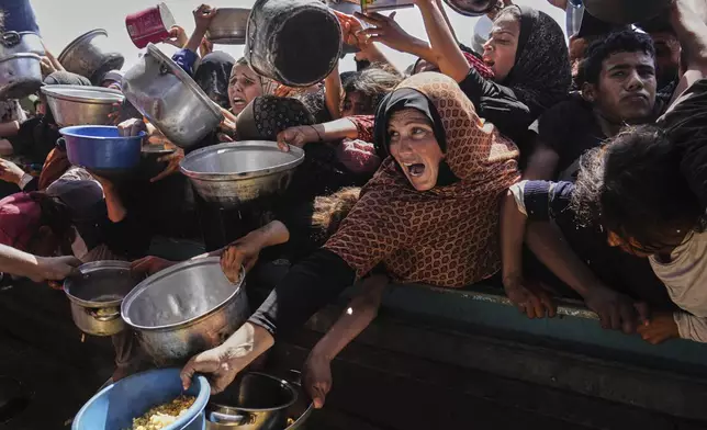 Palestinians struggle to obtain donated food at a community kitchen in Khan Younis, in the southern Gaza Strip, Friday, May 9, 2025. (AP Photo/Abdel Kareem Hana)