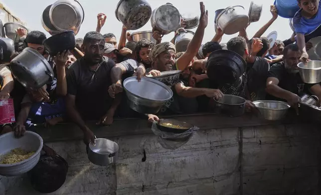 Palestinians struggle to obtain donated food at a community kitchen in Khan Younis, in the southern Gaza Strip, Friday, May 9, 2025. (AP Photo/Abdel Kareem Hana)