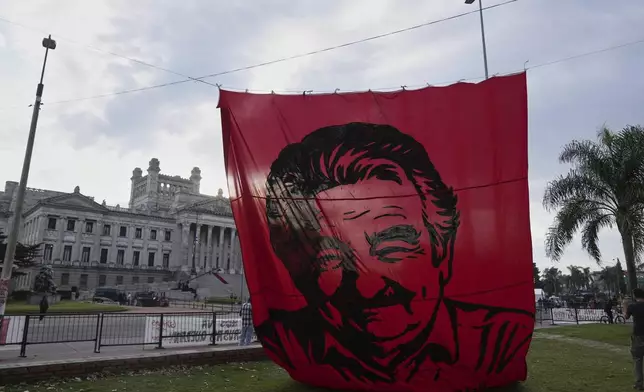 A banner of the late Uruguayan President Jose Mujica hangs outside the Legislative Palace where he lies in state during funeral ceremonies in Montevideo, Uruguay, Thursday, May 15, 2025. (AP Photo/Matilde Campodonico)