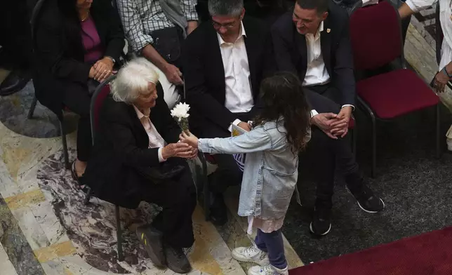 A girl gives a flower to Lucia Topolansky, widow of former Uruguayan President Jose Mujica, during funeral ceremonies for the late leader at the Legislative Palace in Montevideo, Uruguay, Thursday, May 15, 2025. (AP Photo/Matilde Campodonico)