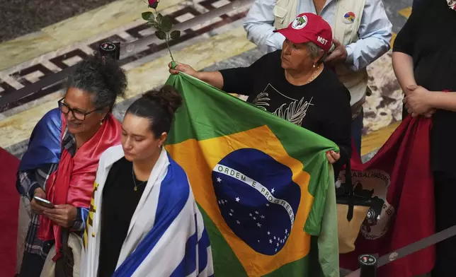 A supporter with a Brazilian flag lines up to pay their last respects to the late Uruguayan President José Mujica during funeral ceremonies at the Legislative Palace in Montevideo, Uruguay, Thursday, May 15, 2025. (AP Photo/Matilde Campodonico)