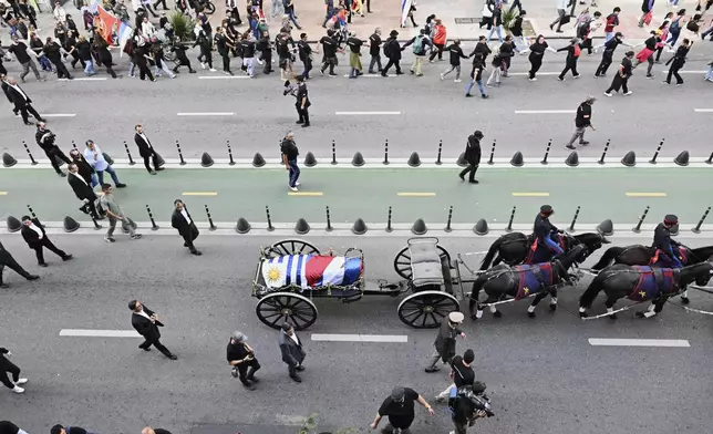 The casket of Uruguay's former President Jose Mujica is transported from the presidential palace to the National Assembly during his funeral procession in Montevideo, Uruguay, Wednesday, May 14, 2025. (AP Photo/Santiago Mazzarovich)