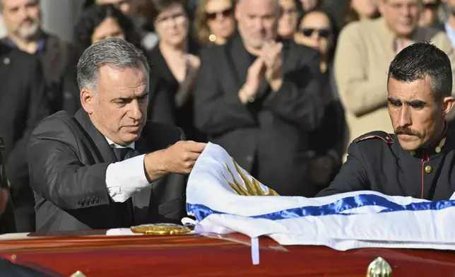 Uruguayan President Yamandu Orsi covers the casket of the late, former Uruguayan President Jose Mujica with the national flag at the presidential palace in Montevideo, Uruguay, Wednesday, May 14, 2025. (AP Photo/Santiago Mazzarovich)