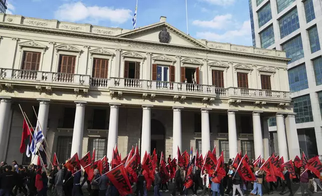 Supporters of the political party "Movimiento de Participación Popular," or Popular Participation Movement, parade past the presidential palace during the funeral of former Uruguayan President Jose Mujica in Montevideo, Uruguay, Wednesday, May 14, 2025. (AP Photo/Matilde Campodonico)