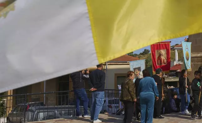 A Vatican flag waves as the worshippers follow a traditional procession on the Feast Day of St. George outside St. George Church in the Maronite village of Kormakitis in the breakaway north of the ethnically divided Cyprus on Wednesday, April 23, 2025. (AP Photo/Petros Karadjias)