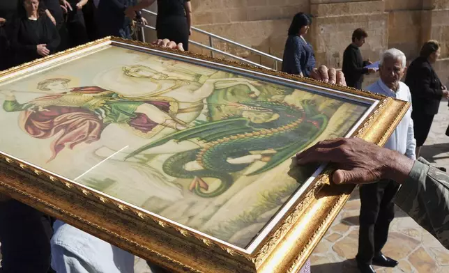 Catholic Maronite faithful pass under the icon of St. George in an act of supplication during a traditional procession on the saint's Feast Day outside St. George Church in the Maronite village of Kormakitis in the breakaway north of the ethnically divided Cyprus on Wednesday, April 23, 2025. (AP Photo/Petros Karadjias)
