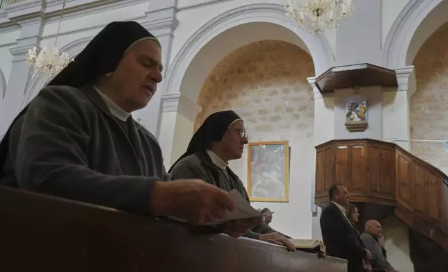 Maronite Catholic nuns recite hymns during a service in outside St. George Church in the Maronite village of Kormakitis in the breakaway north of the ethnically divided Cyprus on Wednesday, April 23, 2025. (AP Photo/Petros Karadjias)