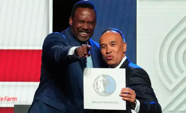 Dallas Mavericks' Rolando Blackman, left, and NBA Deputy Commissioner Mark Tatum, right, pose for photos after Tatum announced that the Mavericks had won the first pick in the NBA basketball draft lottery in Chicago, Monday, May 12, 2025. (AP Photo/Nam Y. Huh)
