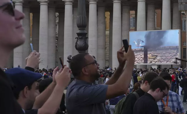 Faithful take photos the black smoke billows from the Sistine Chapel during the conclave to elect a new Pope, at the Vatican, Thursday, May 8, 2025 (AP Photo/Emilio Morenatti)