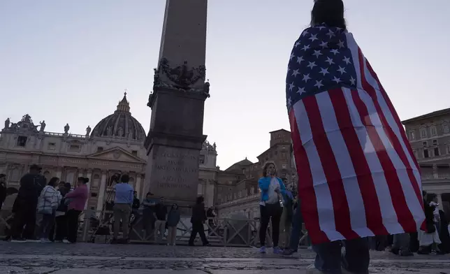 Andrea Gallardo, 20, from Texas, wears an American flag after Pope Leo XIV appeared on the balcony of St Peter's Basilica following his election, at the Vatican, Thursday, May 8, 2025. (AP Photo/Paolo Santalucia)