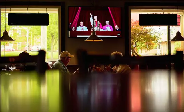 Patrons watch live coverage of the newly elected Pope Leo XIV from St. Peter's Basilica at the Vatican while having lunch at Ron's Roost Chicken Restaurant, Thursday, May 8, 2025, in Cincinnati. (AP Photo/Carolyn Kaster)