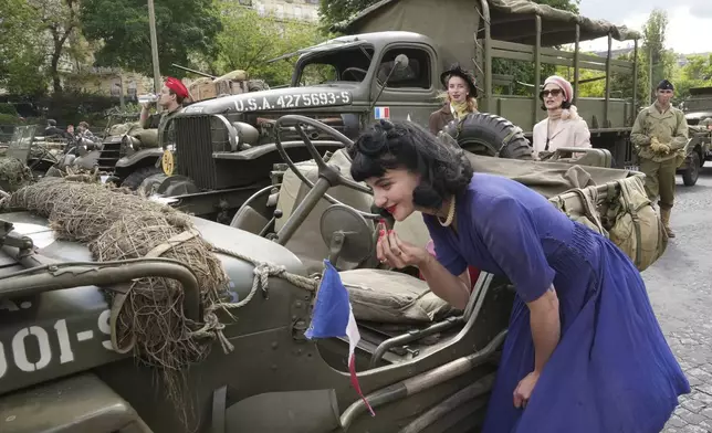A reenactor puts on lipstick before a parade as part of ceremonies marking the 80th anniversary, of the end of World War II in Europe, Thursday, May 8, 2025 in Paris. (AP Photo/Michel Euler)