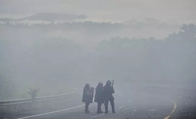 Police stand on the Pan-American Highway after clearing a blockaid by anti-government protesters opposing social security reforms and a Panama-U.S. memorandum concerning the Panama Canal, in El Piro, Panama, Wednesday, May 14, 2025. (AP Photo/Matias Delacroix)