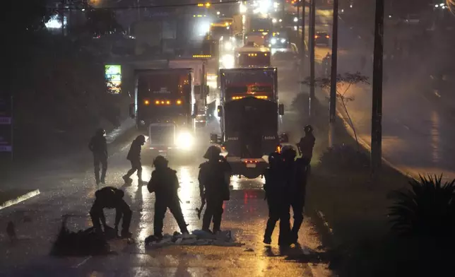 Police clear a highway blocked by anti-government demonstrators protesting the recently signed Panama-U.S. memorandum concerning the Panama Canal and a law that overhauls the social security agency, in Santiago, Panama, Tuesday, May 13, 2025. (AP Photo/Matias Delacroix)