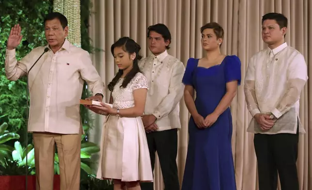 FILE - In this photo provided by the News and Information Bureau, Malacanang Palace, Philippine President Rodrigo Duterte, left, takes his oath before Philippine Supreme Court Associate Justice Bienvenido Reyes during inauguration ceremony in Malacanang Palace, June 30, 2016 in Manila, Philippines. Holding the bible is President Duterte's daughter Veronica. Others in photo are Duterte's children, from right, Paolo Duterte, Sarah Duterte and Sebastian Duterte. (The News and Information Bureau, Malacanang Palace via AP, file)