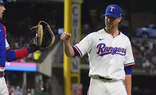Texas Rangers starting pitcher Jacob deGrom, right, reaches out to teammate catcher Jonah Heim after the final out ending the seventh inning of a baseball game against the Houston Astros, Thursday, May 15, 2025, in Arlington, Texas. (AP Photo/LM Otero)
