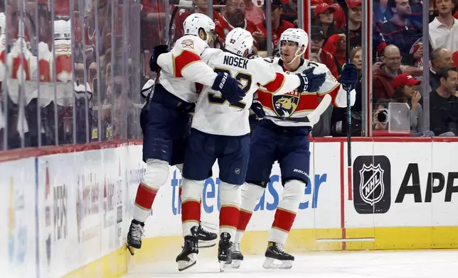 Florida Panthers' A.J. Greer (10) celebrates his goal against the Carolina Hurricanes with teammates Tomas Nosek (92) and Niko Mikkola (77) during the second period of Game 1 of the NHL hockey Stanley Cup Eastern Conference finals in Raleigh, N.C., Tuesday, May 20, 2025. (AP Photo/Karl DeBlaker)