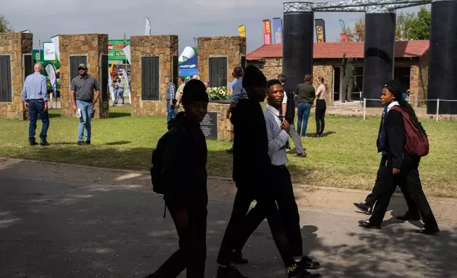 Visitors at the Nampo agricultural fair, one of the largest in the southern hemisphere, walk past the wall of remembrance, a tribute to farmers killed since 1961, near Bothaville, South Africa, May 15, 2025. (AP Photo/Jerome Delay)
