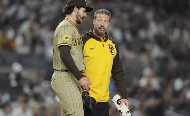 A trainer checks on San Diego Padres pitcher Dylan Cease during the seventh inning of a baseball game against the New York Yankees Wednesday, May 7, 2025, in New York. (AP Photo/Frank Franklin II)