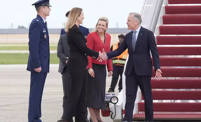 Canada's Prime Minister Mark Carney, right, is greeted by Canadian Ambassador to the U.S. Kirsten Hillman, second left, U.S. Acting Chief of Protocol Abby Jones, and U.S. Col. Randall J. Heusser after he disembarks a government plane Monday, May 5, 2025, as he arrives in Washington. (Adrian Wyld/The Canadian Press via AP)