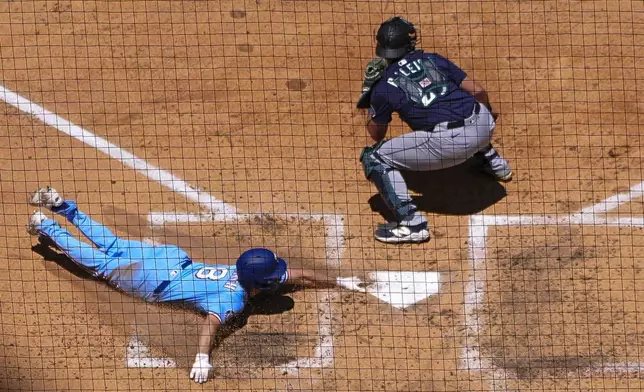 Texas Rangers' Josh Smith, left, slides onto home plate to score on a two-run single by Corey Seager, not visible, as Seattle Mariners catcher Cal Raleigh waits for the throw during the third inning of a baseball game Sunday, May 4, 2025, in Arlington, Texas. (AP Photo/Julio Cortez)