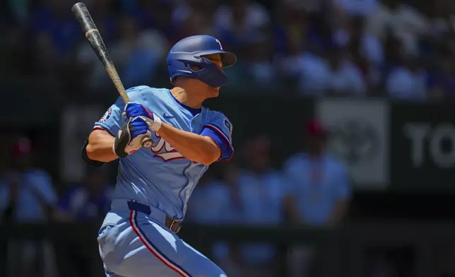 Texas Rangers' Corey Seager follows through while hitting a two-run single against the Seattle Mariners during the third inning of a baseball game Sunday, May 4, 2025, in Arlington, Texas. (AP Photo/Julio Cortez)