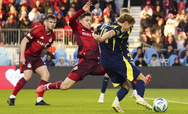 Nashville SC's Jacob Shaffelburg, front right, shoots on goal as Toronto FC's Lazar Stefanovic, center, closes in during first-half MLS soccer match action in Toronto, Saturday, May 24, 2025. (Chris Young/The Canadian Press via AP)