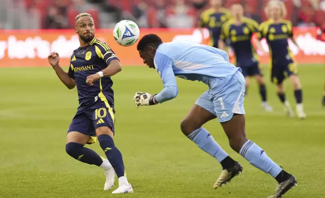 Toronto FC goalkeeper Sean Johnson (1) tries to head the ball away from Nashville SC's Hany Mukhtar (10) after getting caught outside his area during first-half MLS soccer match action in Toronto, Saturday, May 24, 2025. (Chris Young/The Canadian Press via AP)